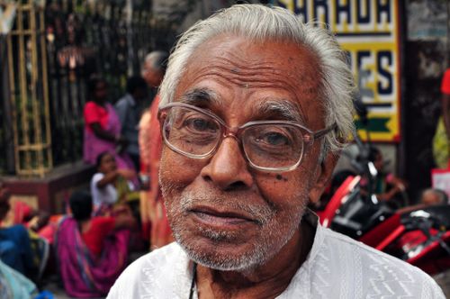 Free Portrait of a senior man with eyeglasses on a vibrant street in Kolkata, India. Stock Photo