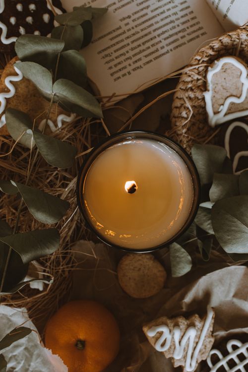 Free A cozy autumn flat lay featuring a lit candle surrounded by seasonal decor and greenery. Stock Photo