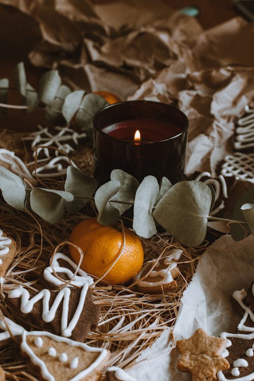 Close-up of a Burning Candle Among Gingerbread Cookies and Christmas Decorations 