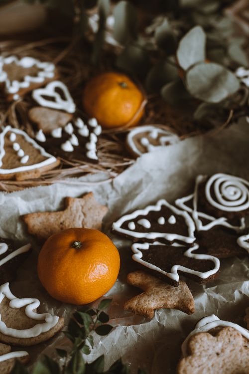 Free Homemade gingerbread cookies and tangerines on parchment, perfect for holiday themes. Stock Photo