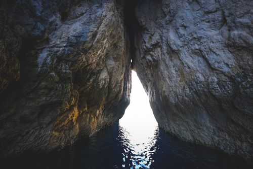 Free Triangle entrance into sea cave in rocky formation with uneven surface under ripple water in daylight Stock Photo