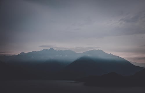 Background of drone picturesque view of silhouette of mountain ridge covered haze under monochrome sky in overcast day