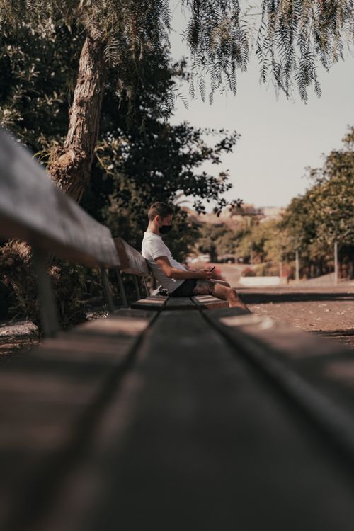 Free An adult man in casual attire sits on a park bench, enjoying a serene day in Santa Cruz de Tenerife. Stock Photo
