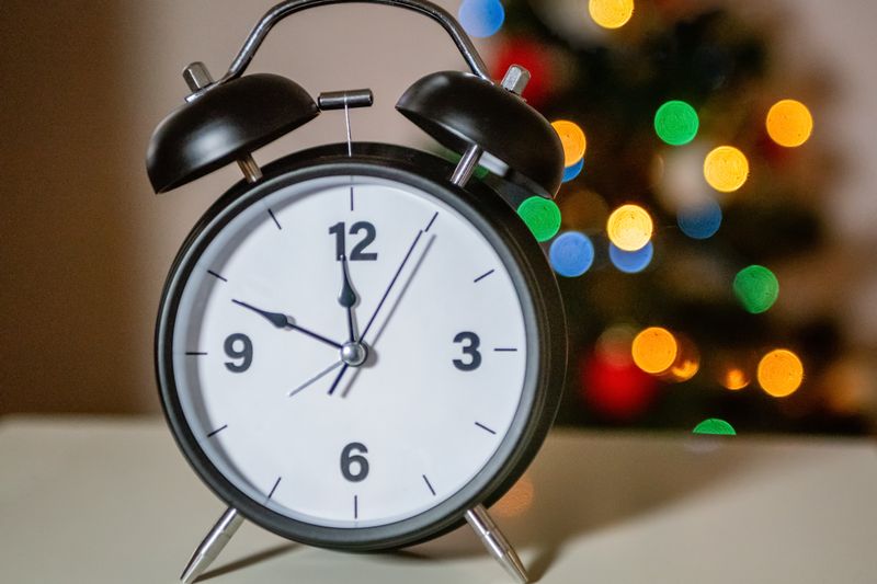 Analog alarm clock with colorful bokeh lights, perfect for holiday themes and time concepts.