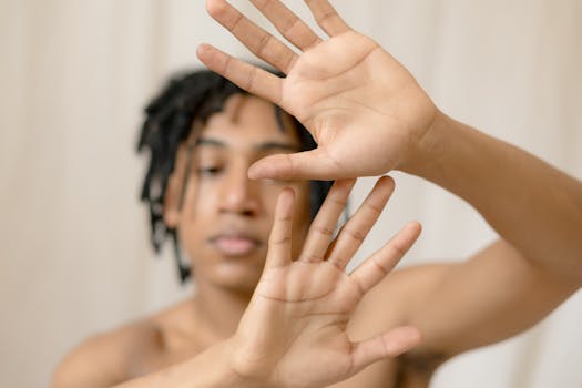 Close-up image of a person with dreadlocks raising hands. Soft focus and neutral background.