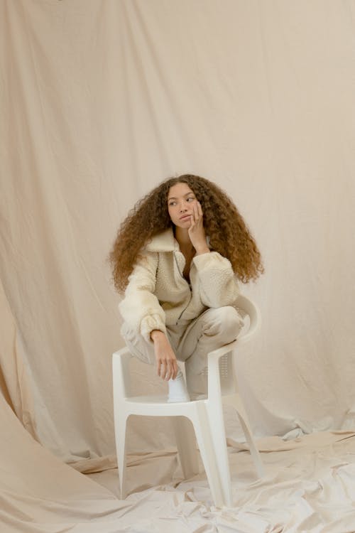 Woman in White Coat Sitting on White Plastic Chair