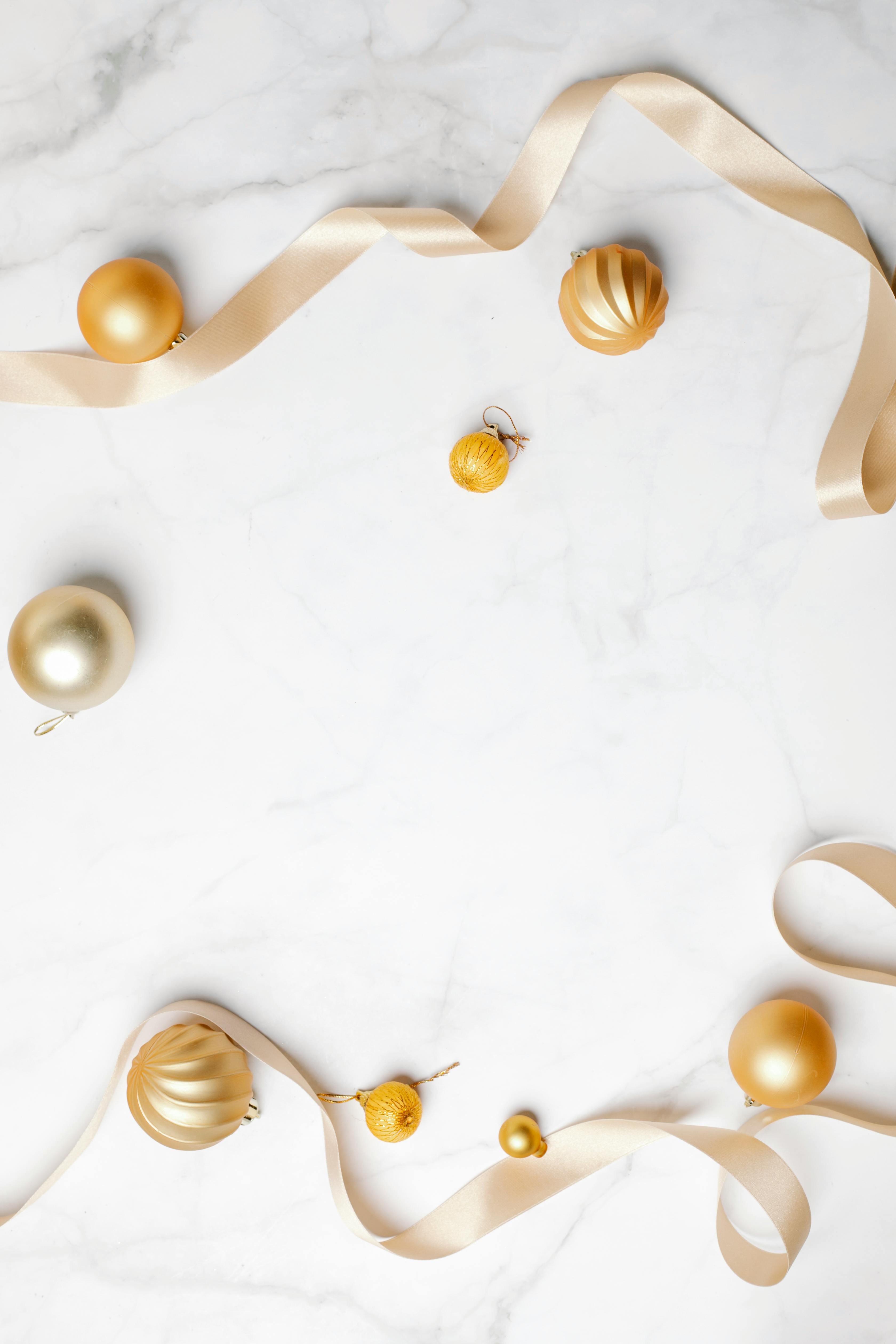 decorative golden baubles and ribbons placed on marble table