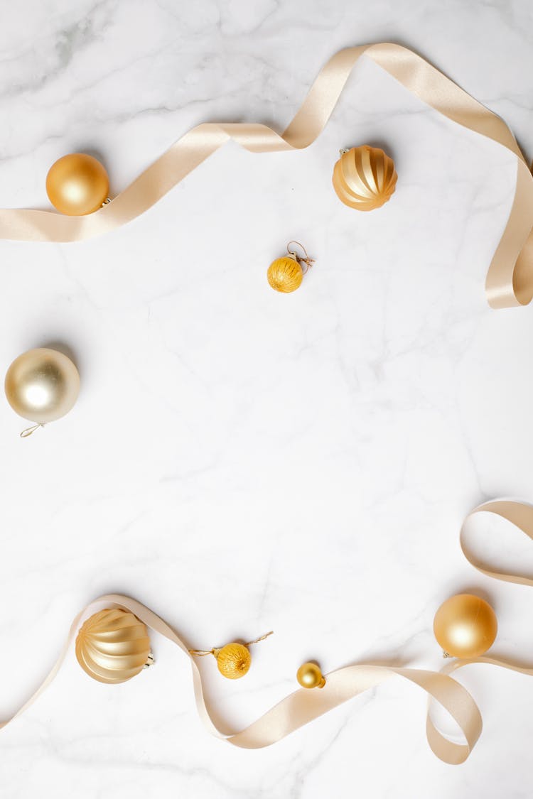 Decorative Golden Baubles And Ribbons Placed On Marble Table