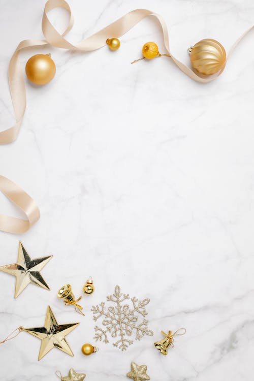 Top view of festive golden baubles with silky ribbons and snowflakes on white background