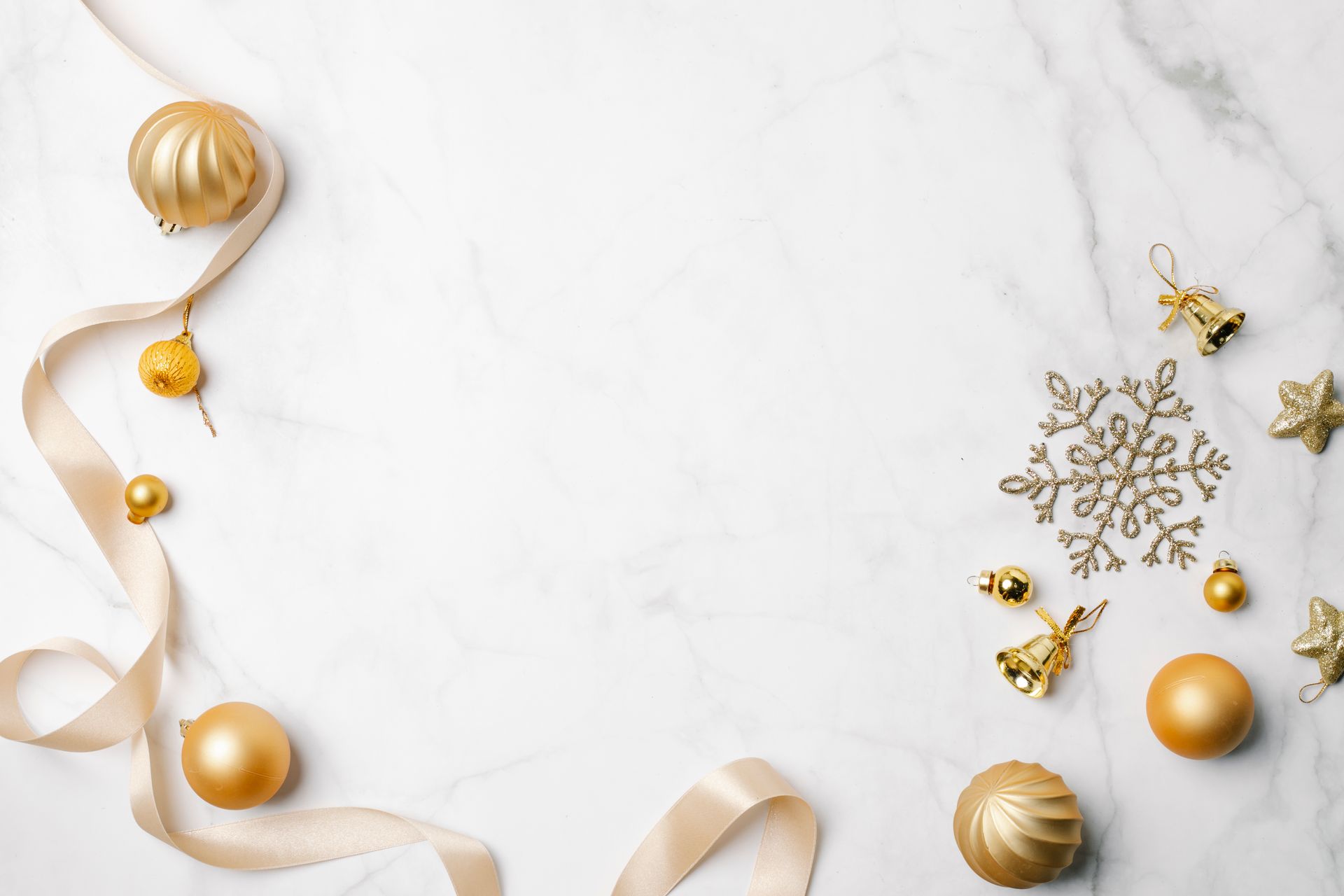 Shiny golden baubles and bells near snowflake and ribbon