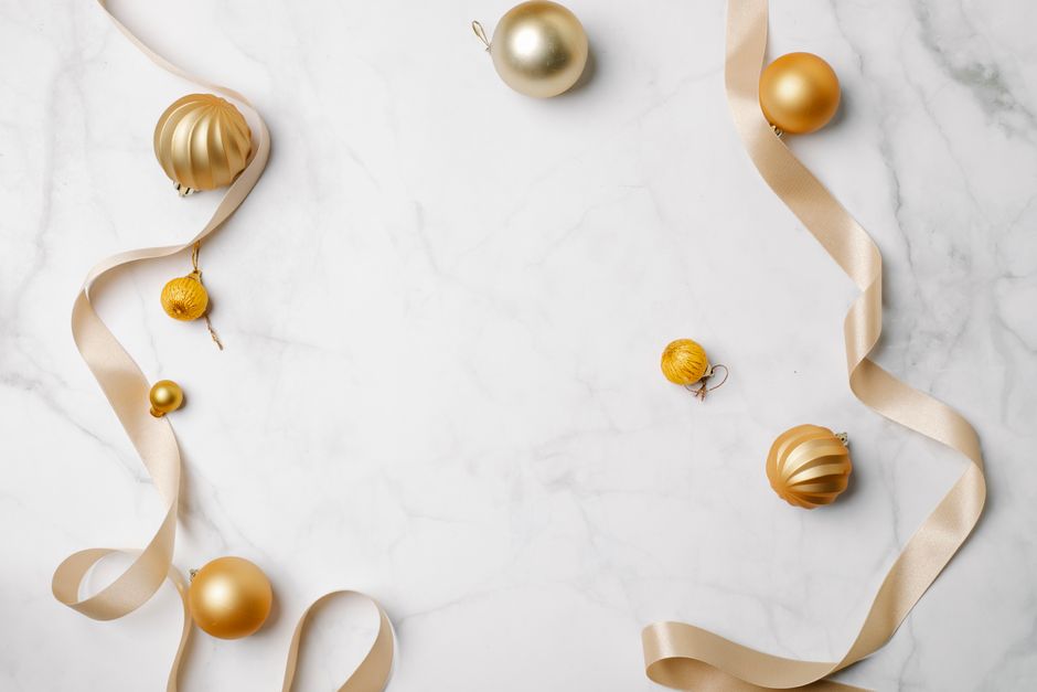 Top view of festive shiny baubles placed near soft ribbon prepared for celebrating Christmas
