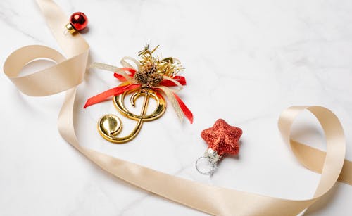 From above of silky ribbon near golden musical note and small Christmas bauble with star