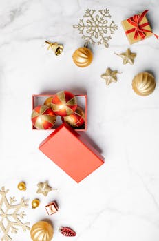 Overhead view of Christmas decorations and gift box on a marble background.