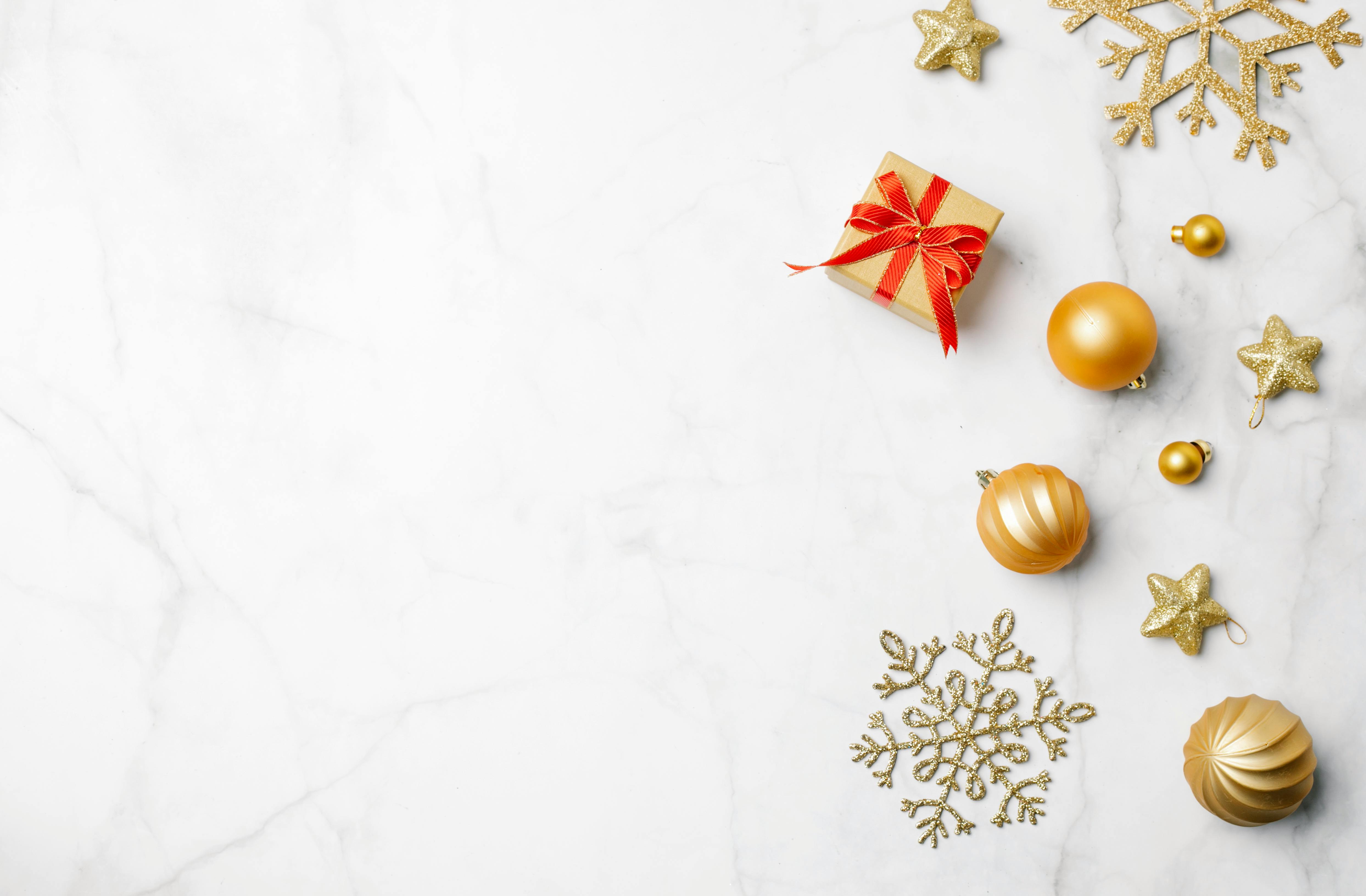 gift box with red ribbon surrounded with christmas baubles