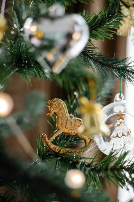 Coniferous tree with decorative heart and horse with garland on branches during New Year holiday at home