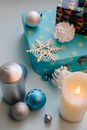 From above of glowing wax candle near decorative balls and snowflake during New Year holiday on gray background