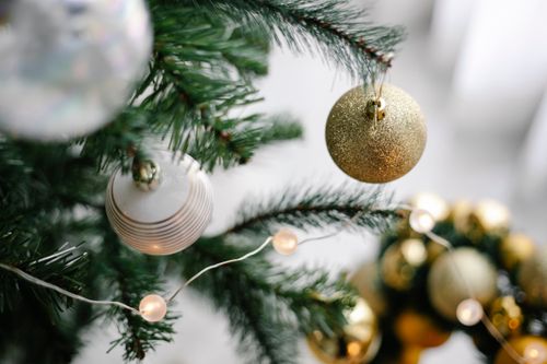 Free From above of decorated coniferous tree with baubles and glowing garland during New Year holiday at home Stock Photo