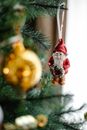 Decorative Saint Nicholas hanging on fir tree with shiny bauble during New Year holiday in house