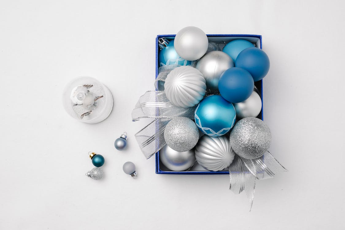 Top view of decorative different New Year baubles in box prepared for celebrating festive holiday on white background