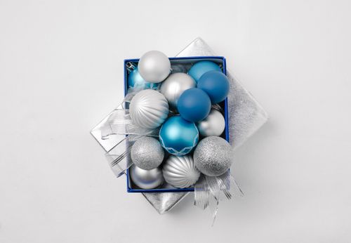 Free Top view of silver and blue balls placed on lid of gift box with ribbon on white background during Christmas holiday Stock Photo