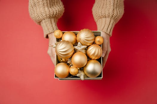Golden Christmas ornaments held above a red background, perfect for holiday decorations.