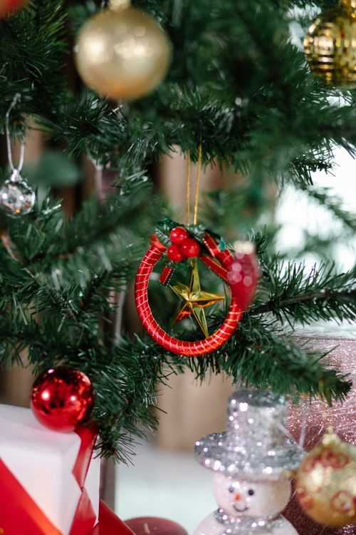 Free Branches of coniferous tree decorated with baubles star and red Christmas toy in light room with snowman on blurred background Stock Photo