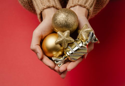 Free Top view of unrecognizable woman holding in hands Christmas hanging shiny golden baubles Stock Photo