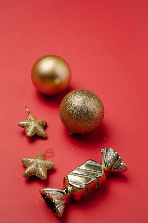 Free From above composition of small shiny golden hanging stars and baubles on red background Stock Photo