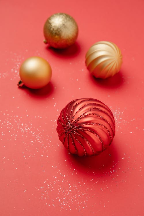 From above of Christmas red and golden baubles sprinkled with shiny glitters on red background