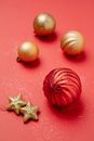 From above Christmas composition of hanging shiny baubles and stars on red background