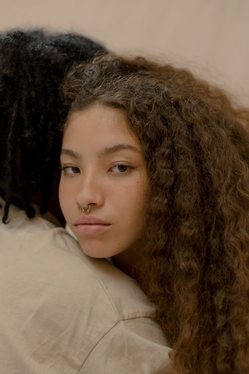 Free Intimate close-up of a young woman with curly hair resting gently. Emotional expression captured. Stock Photo