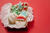 High angle of small box with Christmas biscuits decorated with colourful icing on white doily