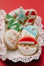 Composition of small box with colourful cookies on white lacy doily on red background