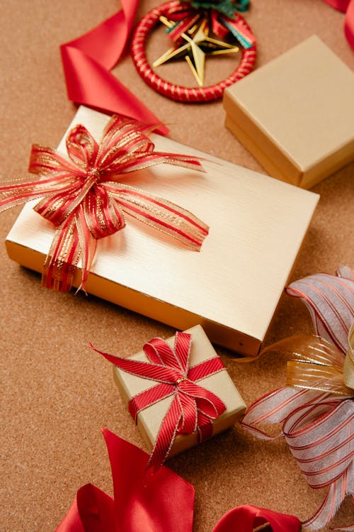 High angle of traditional Christmas gift boxes wrapped in golden paper and decorated with red ribbons