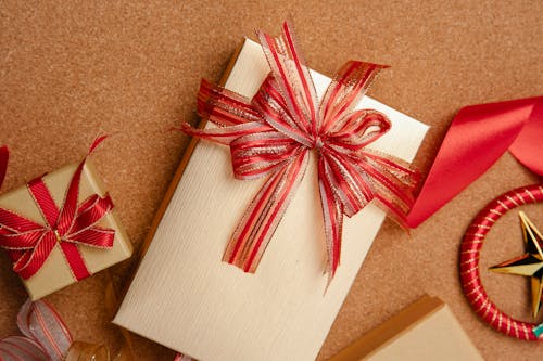 From above of big and small boxes wrapped in golden paper and decorated with red ribbons on table