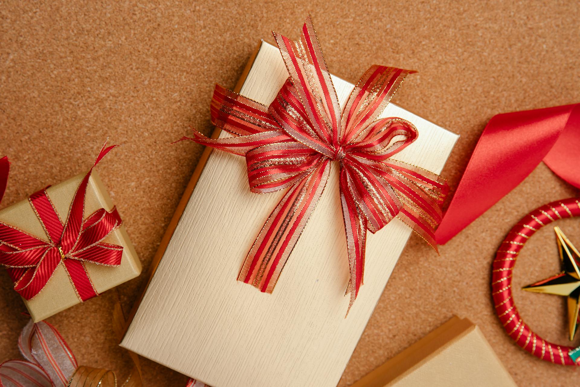 From above of big and small boxes wrapped in golden paper and decorated with red ribbons on table