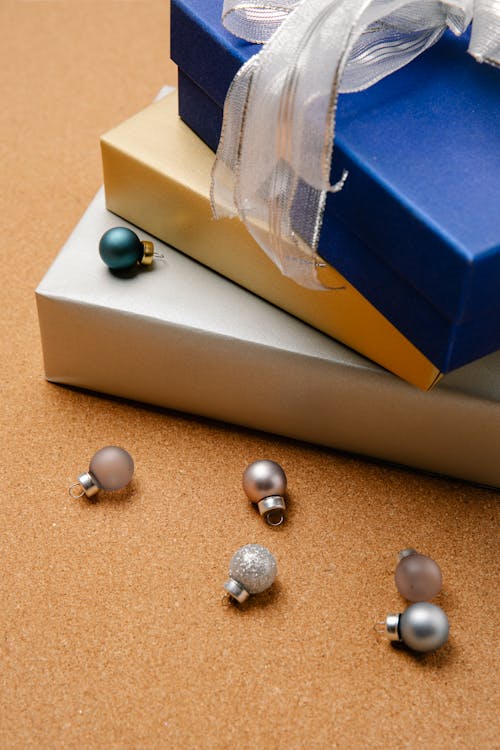 Free High angle of stack of colourful wrapped Christmas gift boxes and small baubles beside Stock Photo