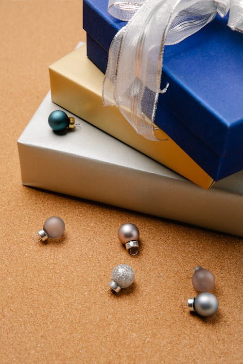 High angle of stack of colourful wrapped Christmas gift boxes and small baubles beside