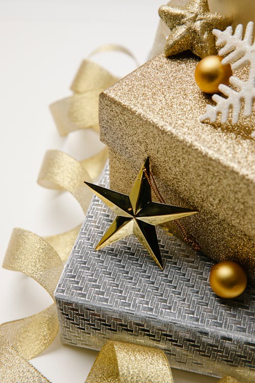 Christmas composition of gift boxes wrapped in silver and golden paper with shiny baubles and twisted ribbon