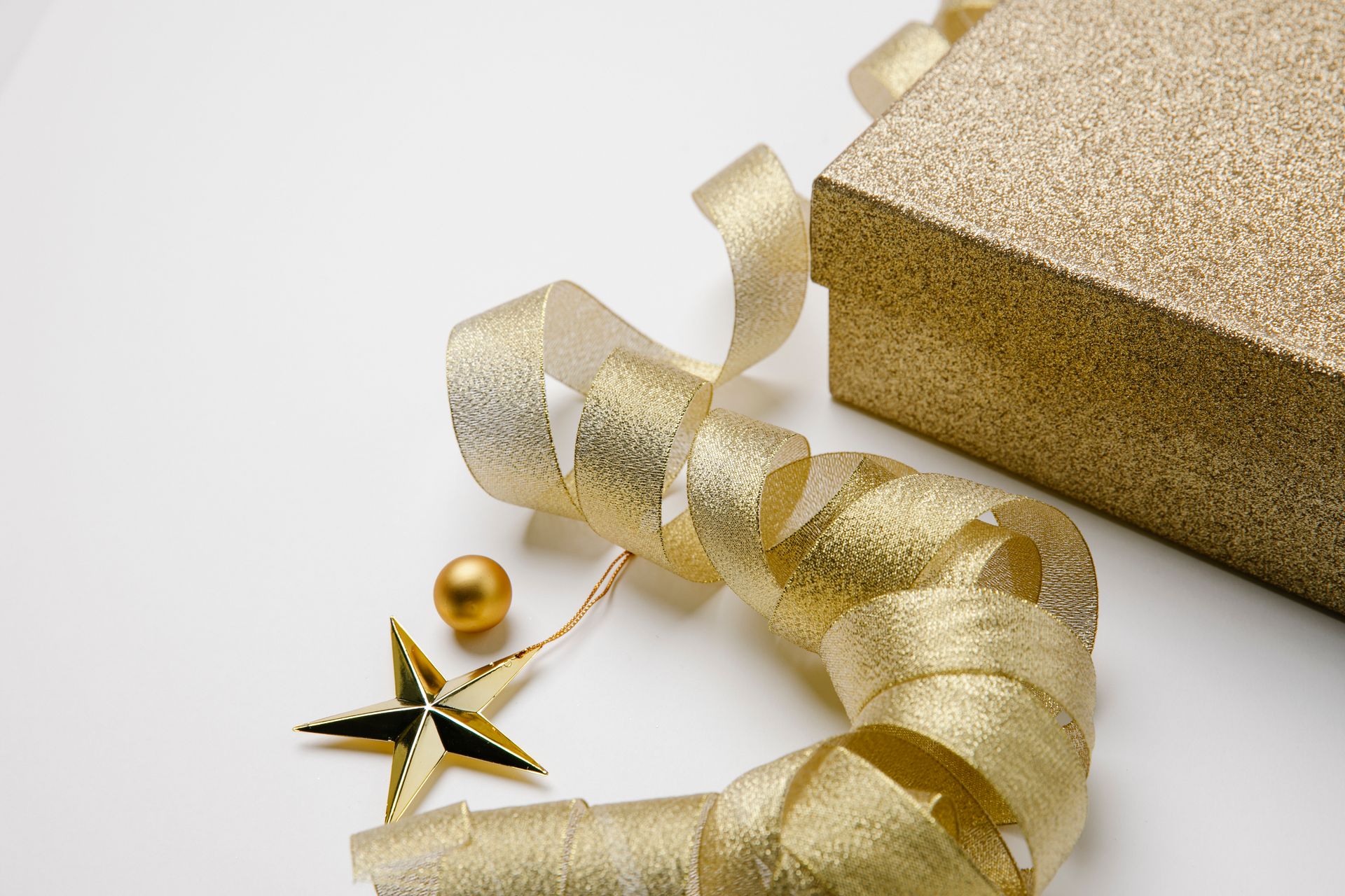 A stylish gold gift box with a shimmering ribbon and star ornament, perfect for holiday celebrations.
