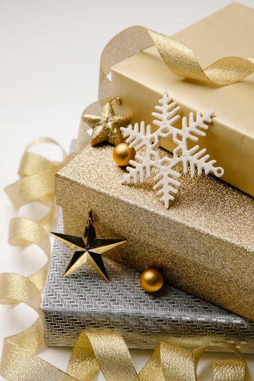 Christmas composition of stack of gift boxes wrapped in silver and golden paper cute baubles and wavy ribbon