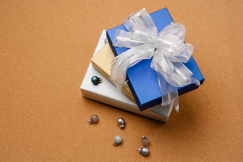 сине белая коробка с белой лентой на коричневом столе