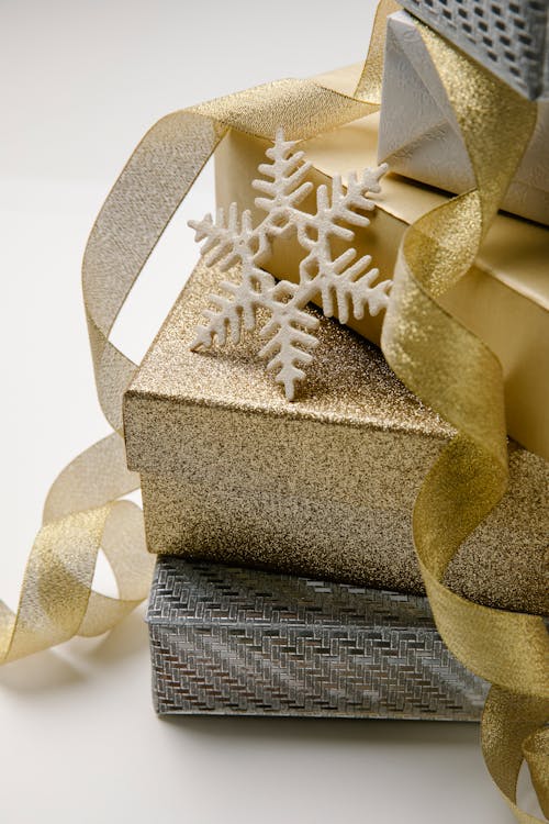 Stack of Christmas gift boxes in silver and golden paper cute snowflake and twisted shiny ribbon