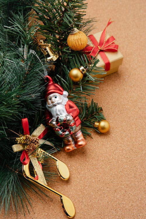 From above of Christmas composition of green fir branch decorated with small bright baubles and little Santa