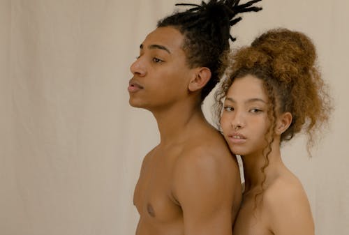 Shirtless Man Standing in Front of a Woman With Long Curly Hair
