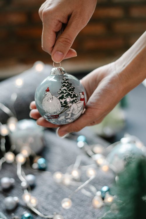 Free Unrecognizable woman with decorative hanging bauble with painted Christmas characters on blurred background Stock Photo