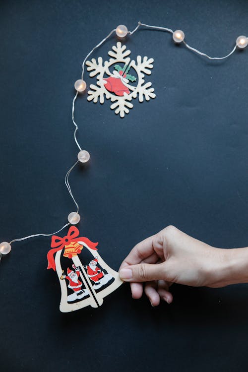 From above of unrecognizable woman with paper piece for garland making decorations for Christmas party