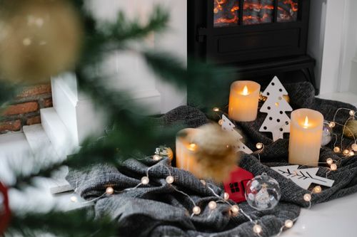 Free Festive decorations with candles and garland near fireplace in room with Christmas tree Stock Photo