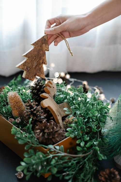 Free Crop anonymous person putting small Christmas decorations in box placed in light room in daylight Stock Photo