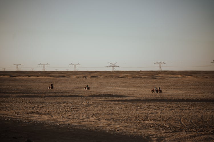 People Riding Quad Bikes In A Desert